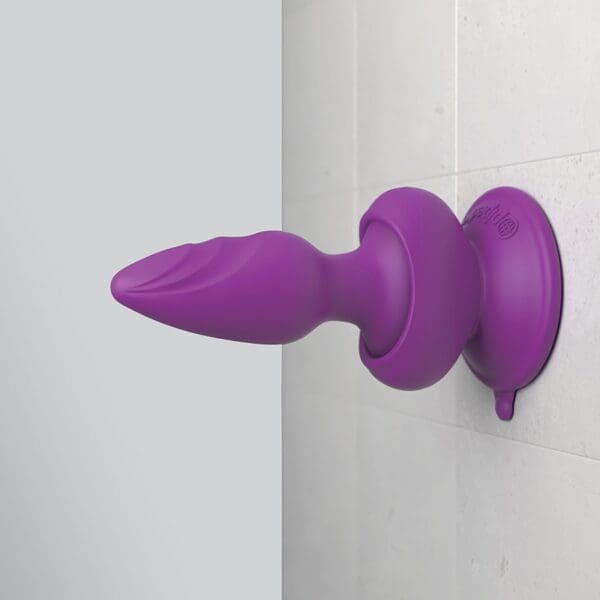 A purple butt plug is hanging on the wall.