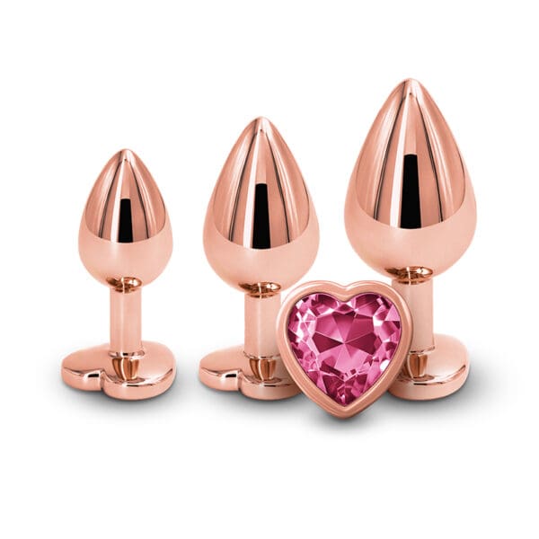 A group of four pink metal plugs with one heart shaped gem.