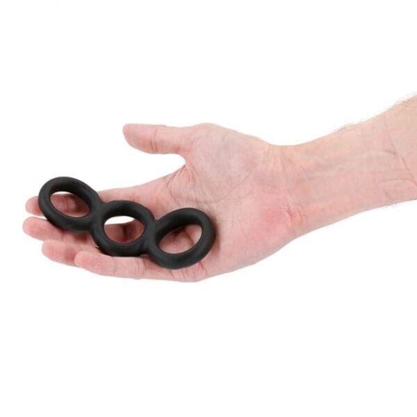 A hand holding three black rubber rings.