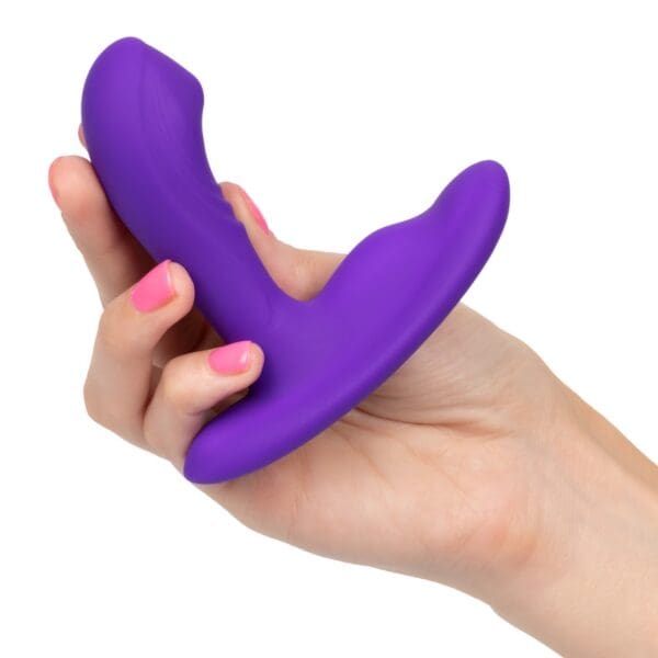 A person holding a purple dildo in their hand.