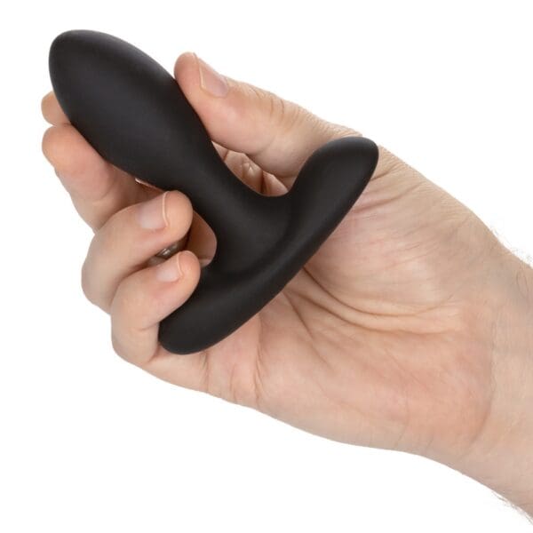 A person holding a black dildo in their hand.