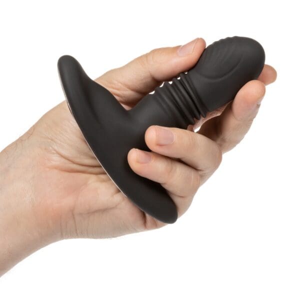 A person holding a black sex toy in their hand.